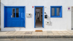 A building with a white facade, two blue-framed doors, a visible number '20' on the wall, and a no parking sign. - Vacation Home 'Casa Fela' with Wi-Fi (Caleta de Famara)