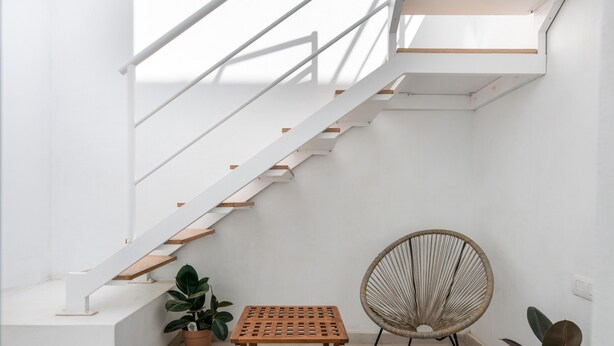 A staircase with white railings and wooden steps, a small wooden table, a wicker chair, and potted plants. - Vacation Home 'Casa Fela' with Wi-Fi (Caleta de Famara)