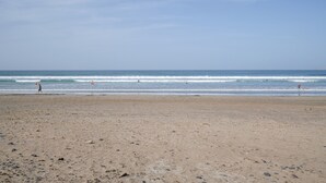 A beach with a clear sky, calm sea, and a few people in the distance. - Vacation Home 'Casa Fela' with Wi-Fi (Caleta de Famara)