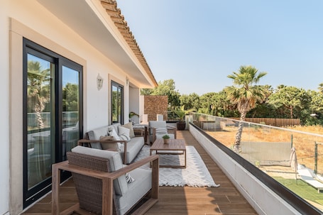 A balcony with a sofa, chairs, a table, and a potted plant.. Villa 'Vila Exclusiva Na Praia De Tróia' with Sea View, Wi-Fi and Air Conditioning