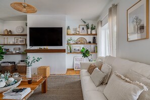A living room with a flat-screen TV, wooden shelves, a white sofa, and a coffee table.