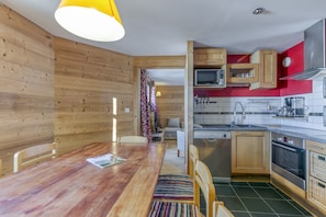 Una cocina compacta con armarios de madera, un microondas y un lavamanos.