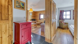 Un intérieur en bois avec un meuble rouge, un coin repas, un canapé et une fenêtre avec des rideaux.
