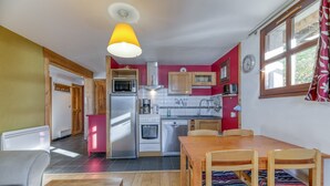 Uma cozinha compacta com eletrodomésticos modernos, um espaço de refeições com móveis de madeira e uma luminária pendente iluminada.