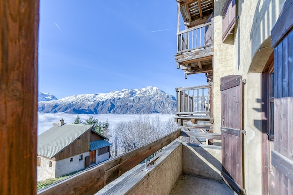 Une vue sur la montagne, avec un balcon en bois et un bâtiment doté d’un toit en pente.