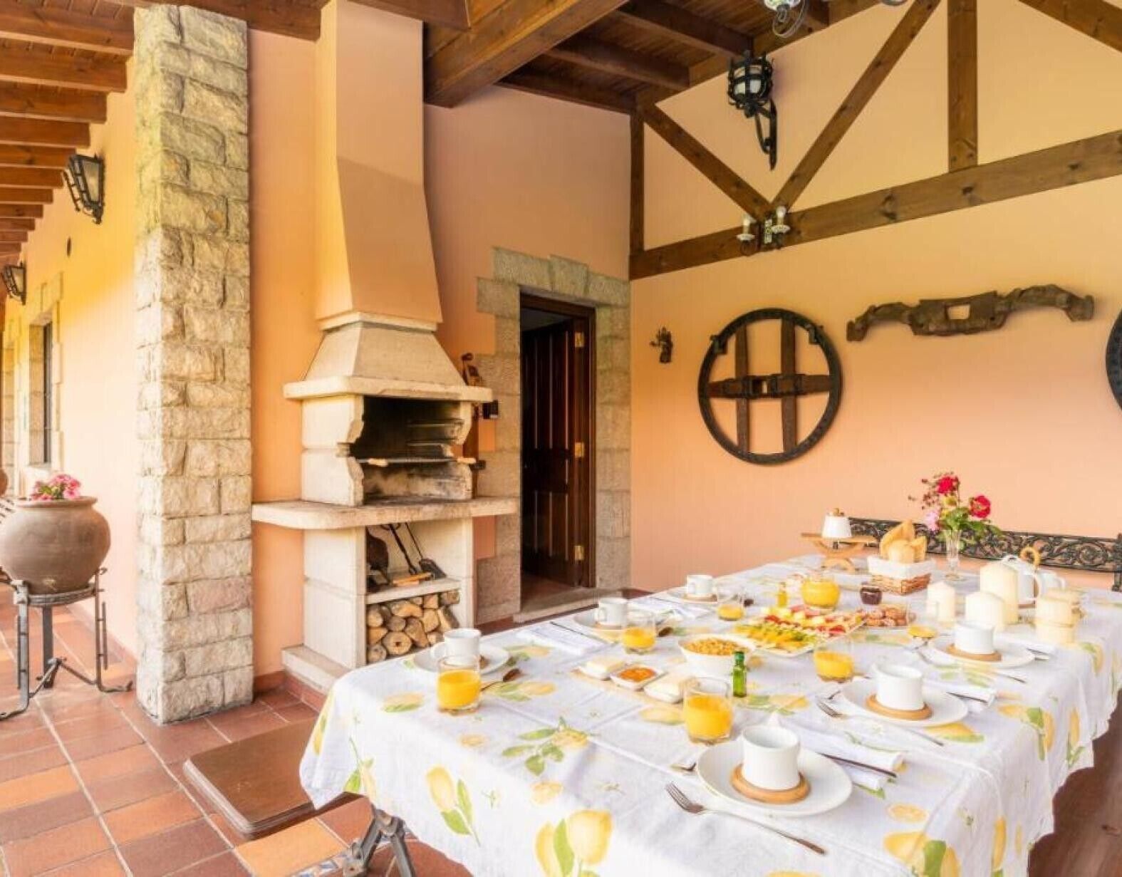 A rustic dining area with a stone oven, a table set for breakfast, and a stone pillar.