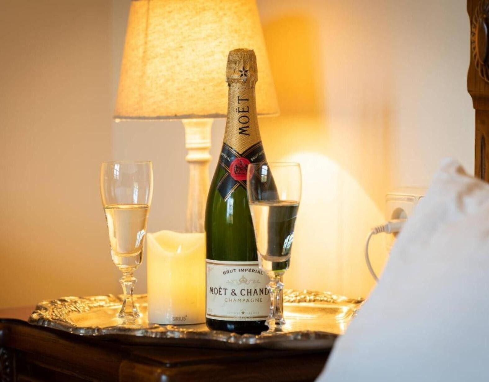 A bottle of Moët & Chandon champagne, two glasses, a candle, and a lamp on a tray.