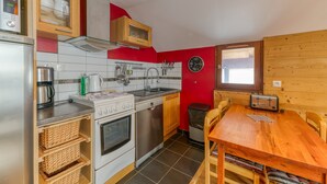 A compact kitchen with a stove, sink, and wooden cabinets. - Apartment 'Regain 7' with Mountain View and Balcony (Villard-Reculas)