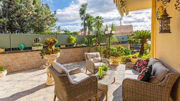 A patio with wicker furniture, potted plants, and a stone wall. - Villa 'Villetta Mare E Monti' with Sea View, Wi-Fi and Air Conditioning (Mascali)