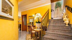 A staircase with a wooden handrail, a marble floor, a rug, a chair, a table with a vase of flowers, and a framed picture on the wall. - Villa 'Villetta Mare E Monti' with Sea View, Wi-Fi and Air Conditioning (Mascali)