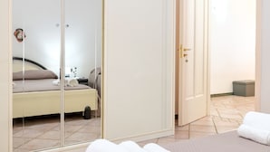 Une chambre à coucher avec un lit, une table de chevet, un miroir et une armoire.