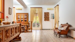 Une pièce spacieuse comprenant un meuble en bois, un canapé, une table à manger et une grande fenêtre avec des rideaux.
