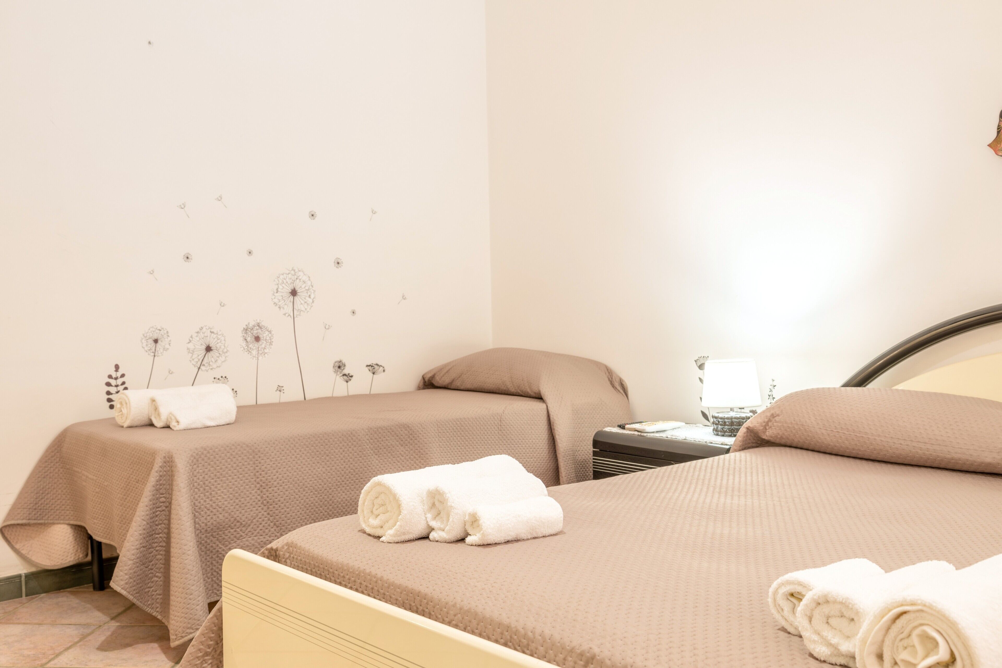 A hotel room with two beds, each with a brown bedspread and white towels.