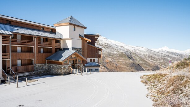 Ein Skiortgebäude mit mehreren Stockwerken, einem Steinsockel und einem Skiliftbereich.