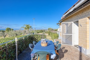 Une terrasse avec une table et des chaises, un panier et une vue sur le paysage.