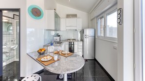 A modern kitchen with white cabinets, a granite countertop, and a refrigerator.