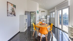 A modern kitchen with a dining area, large windows, and a view of the outdoors.