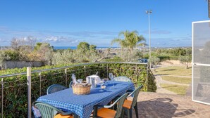A table set outdoors with a view of the sea, a basket, and a metal container.