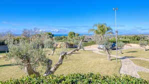 A landscaped outdoor area with a clear view of the sea, a paved pathway, and a street lamp.