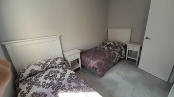 Une chambre avec deux lits, une table de chevet, une commode et une porte.