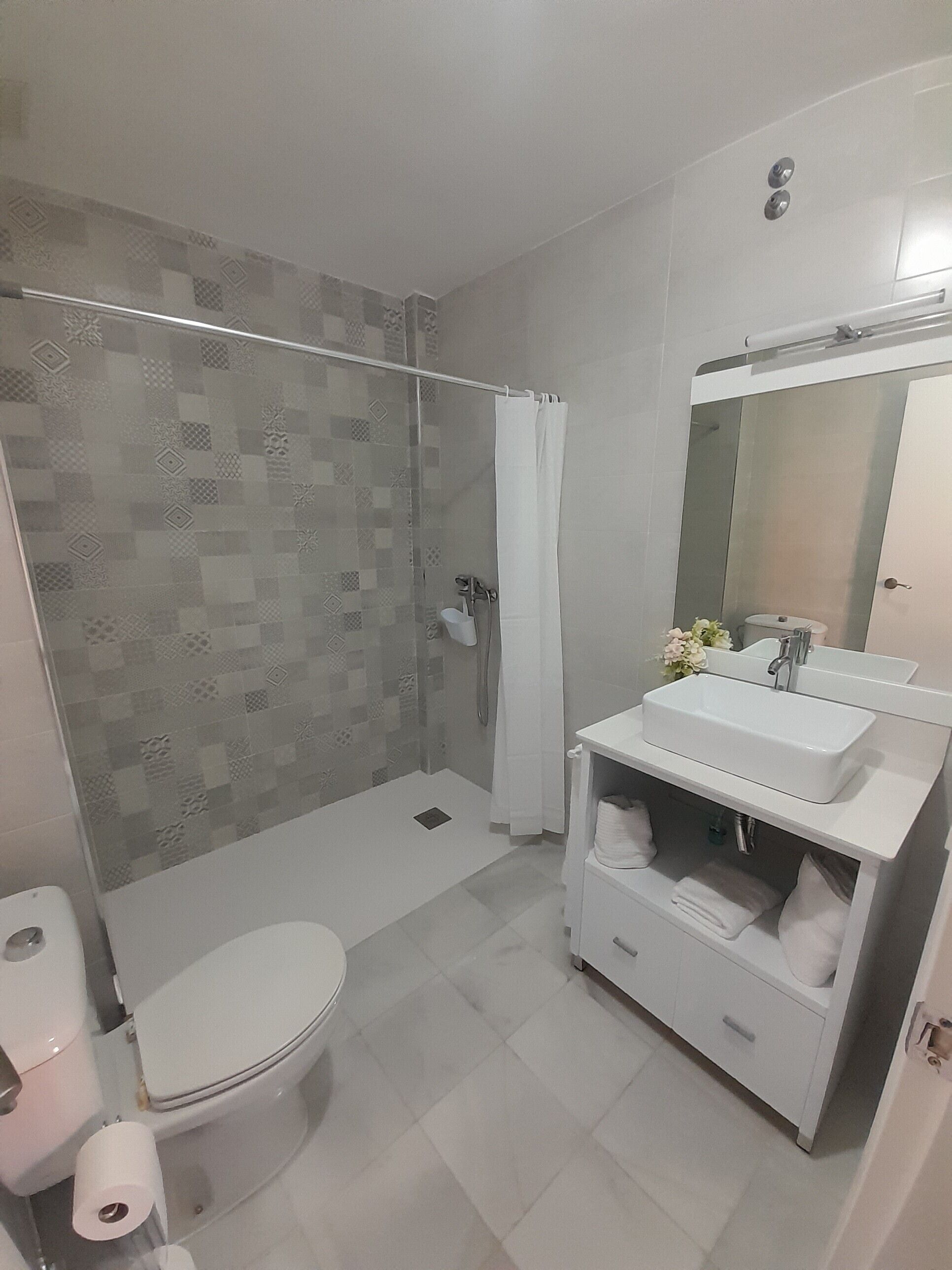A modern bathroom with a shower, toilet, and vanity.