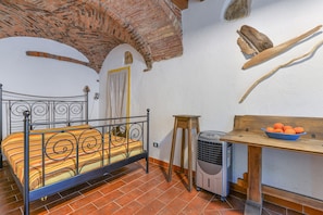 A room with a bed, a heater, a table with a bowl of fruit, and a rustic brick ceiling. - Farmhouse 'Amandolo - Palmenti' with Sea View, Wi-Fi and Air Conditioning (Cavo)