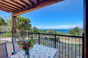 A balcony with a table, a vase with flowers, and a view of the sea. - Apartment 'Amandolo - Arco' with Sea View, Wi-Fi and Air Conditioning (Cavo)