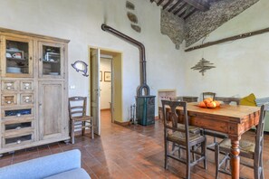 A rustic kitchen with a wooden cabinet, a stove, and a dining table with chairs.