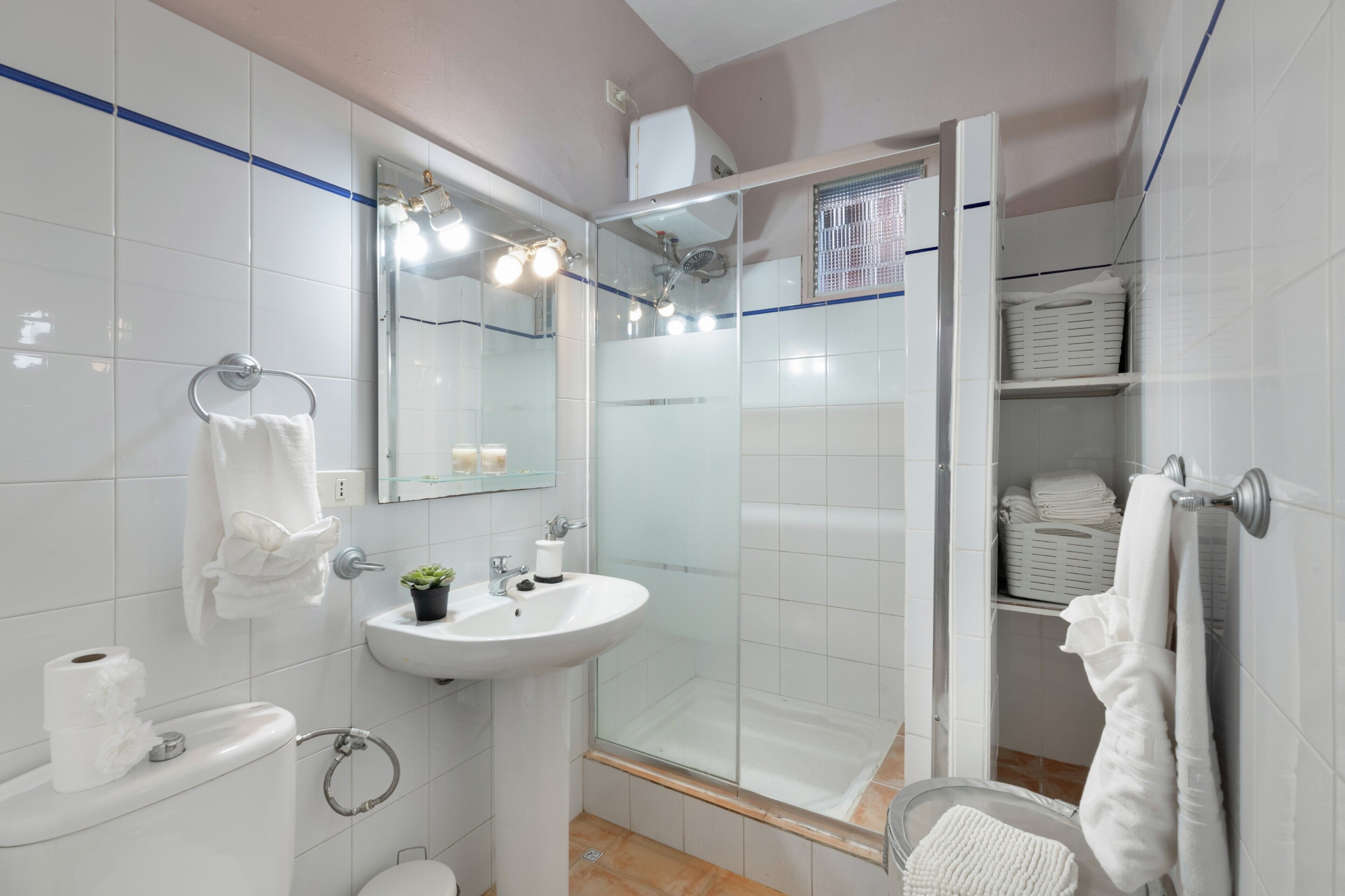 Een moderne badkamer met een douchecabine van glas, een wastafel, een toilet en een spiegel met verlichting.