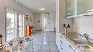 A kitchen with a large window, a sink, and a countertop with kitchen utensils.