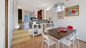 Ein modernes Wohnzimmer mit Essbereich, einer Treppe und einem Bücherregal.