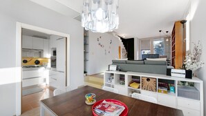 Ein moderner Wohnraum mit Essbereich, Küche und einer gemütlichen Sitzecke mit Sofa und Fernseher.