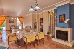 Un comedor con mesa de vidrio, sillas, chimenea y una pared azul de acento.