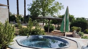 A hot tub surrounded by wooden steps, palm trees, and a green umbrella in a landscaped outdoor area. - Villa 'Santa Ana' with Private Pool, Wi-Fi and Air Conditioning (La Carlota)