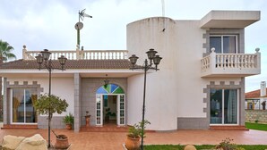 A two-story building with a balcony, a tiled entrance, and a small garden area. - Villa 'Santa Ana' with Private Pool, Wi-Fi and Air Conditioning (La Carlota)