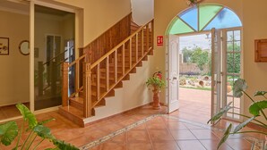 A staircase with wooden railings leading to an open door, a potted plant, and a tiled floor. - Villa 'Santa Ana' with Private Pool, Wi-Fi and Air Conditioning (La Carlota)