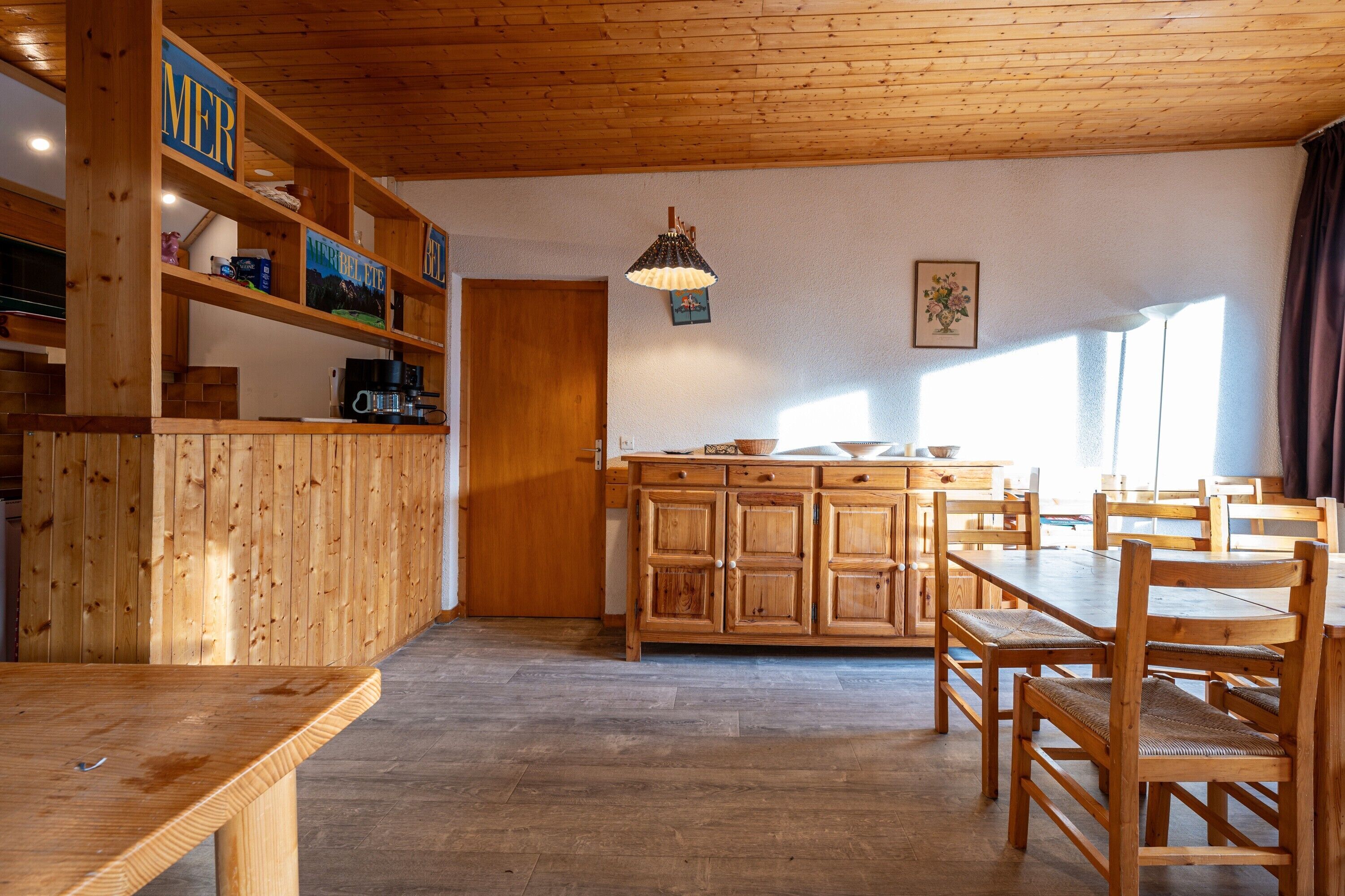 Interior de madera con área de cocina, mesa y sillas.