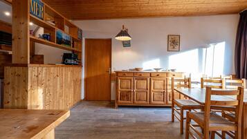 Interior de madera con área de cocina, mesa y sillas.