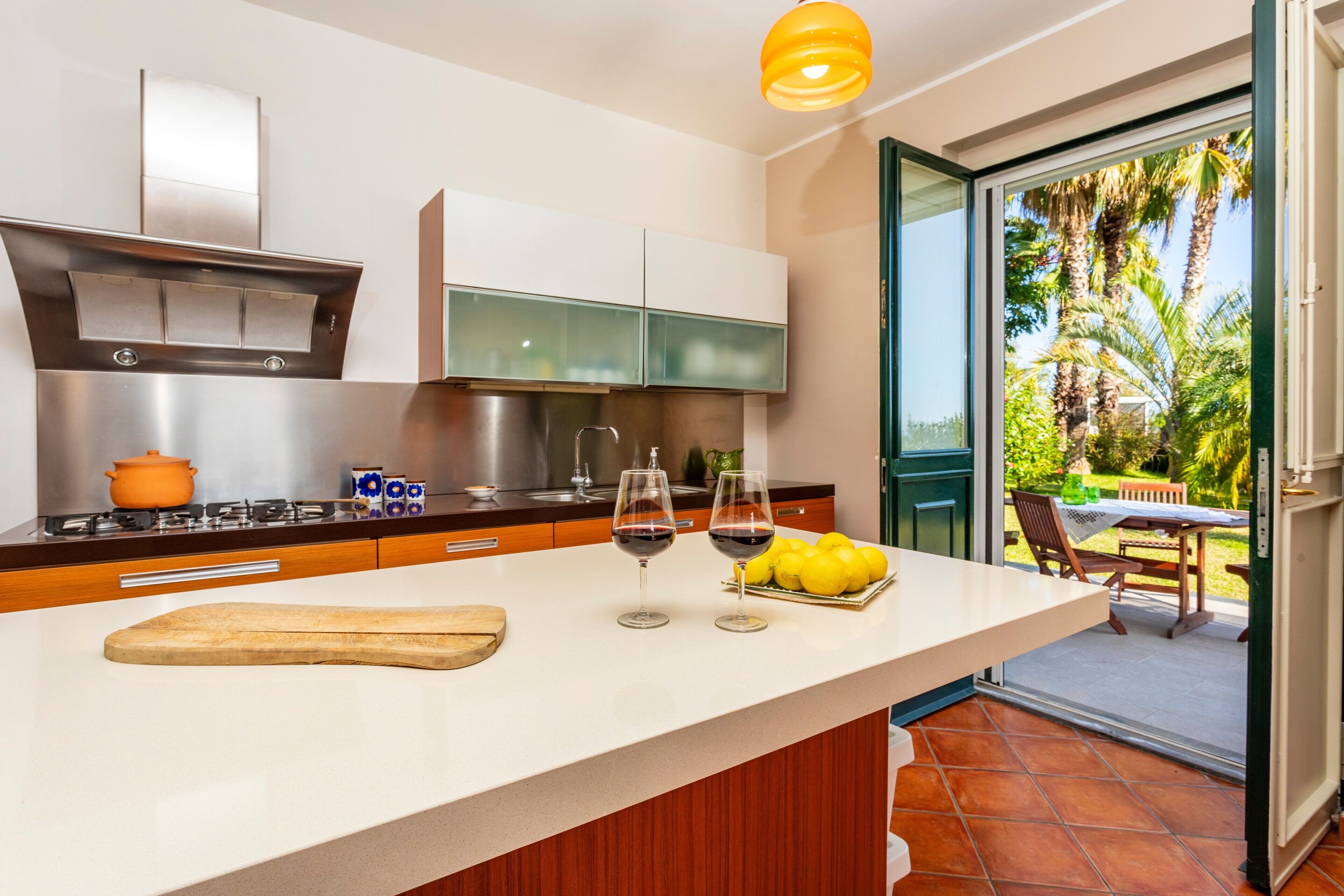 Una cocina moderna con una isla grande, una estufa a gas y vistas a un patio con mobiliario exterior.