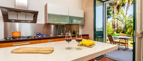 Una cocina moderna con una isla grande, una estufa a gas y vistas a un patio con mobiliario exterior.