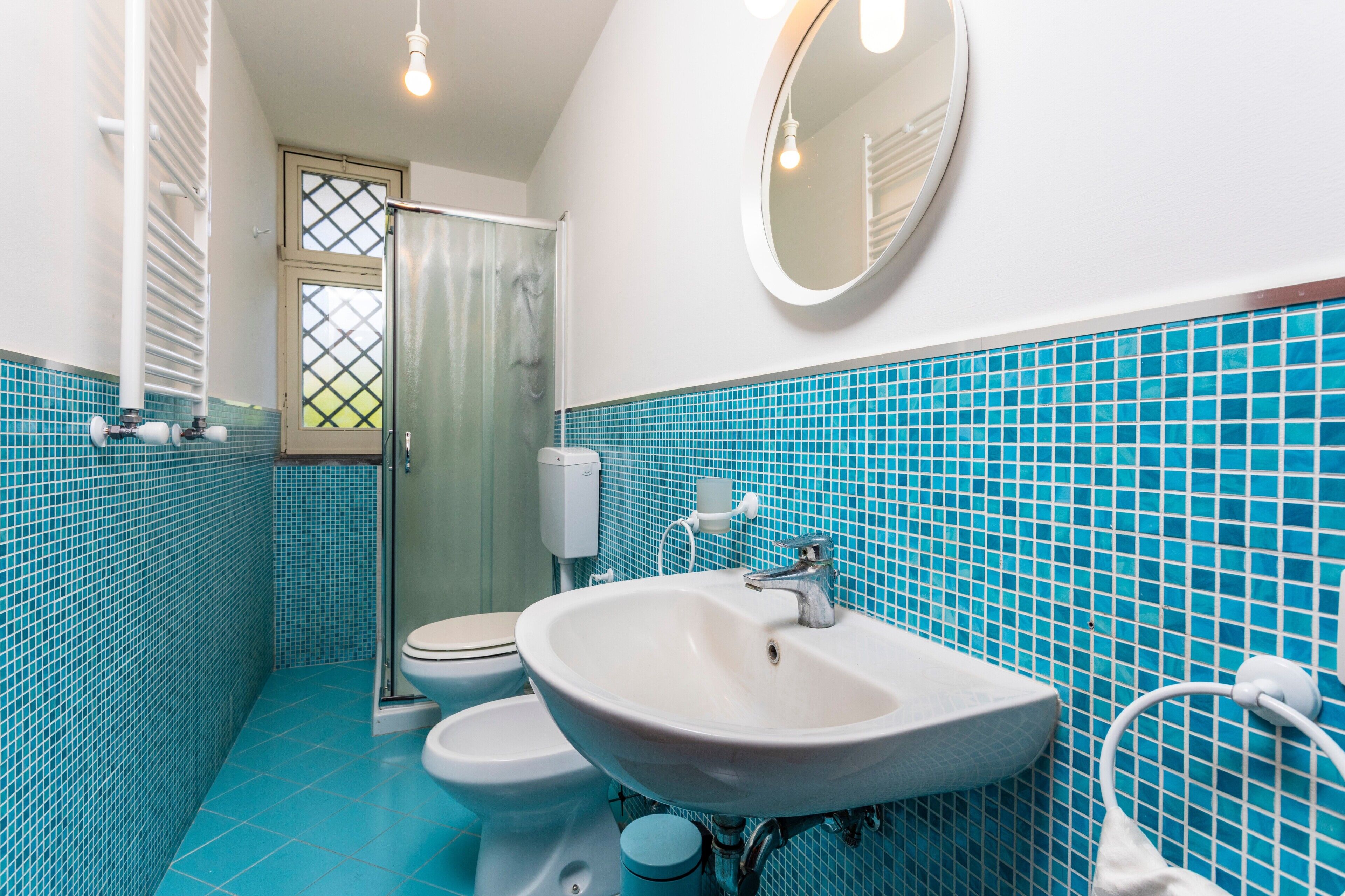 Een badkamer met een wit wastafelmeubel, toilet en douche.