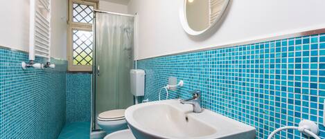 Een badkamer met een wit wastafelmeubel, toilet en douche.