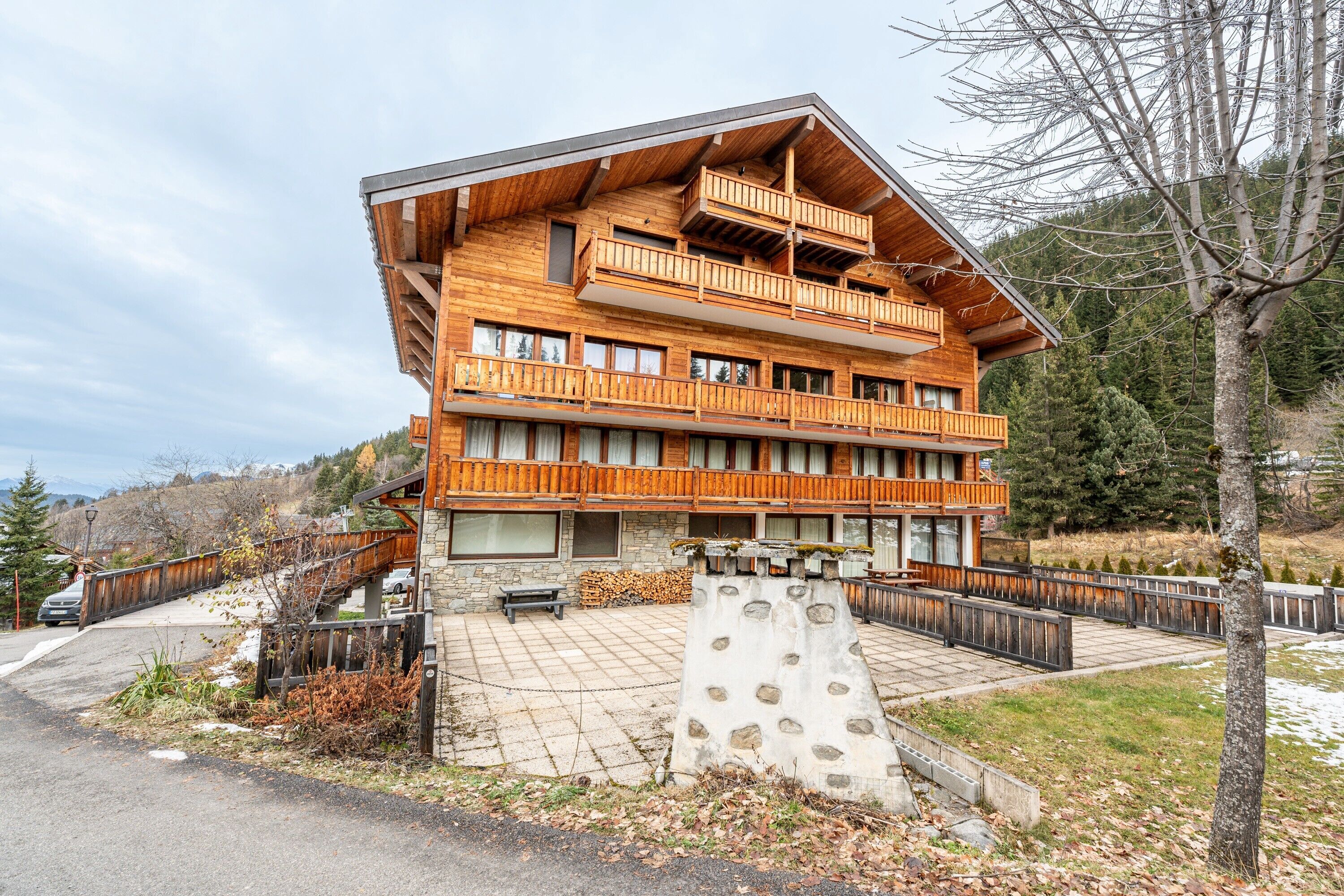 A multi-story wooden building with balconies, a stone facade, and a paved courtyard.