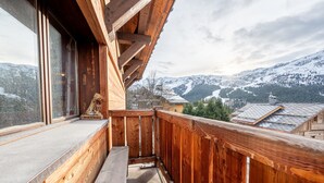 A wooden balcony with a view of snow-covered mountains.