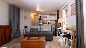 Un espacio habitable compacto con kitchenette, un sofá, un baúl de madera y un comedor.