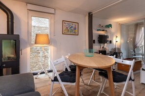 Un salon chaleureux avec une cheminée, une table à manger avec des chaises, un canapé et un mur en pierre.