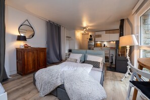 Une chambre à coucher avec un lit, une commode, un miroir et, au fond, un coin cuisine.
