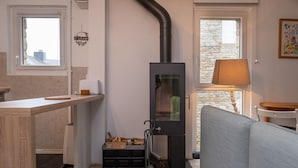 Cocina compacta con estufa integrada, encimera de madera y ventana con vistas a un muro de piedra.