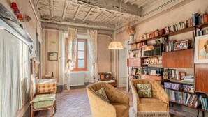 A room with a fireplace, a bookshelf, a window, and a door. - Villa Gabriella with Beautiful Garden (Piazzano)