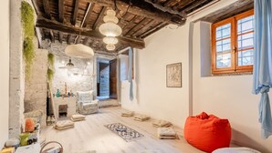 A rustic room with exposed wooden beams, a patterned rug, and a red bean bag. - Villa Gabriella with Beautiful Garden (Piazzano)
